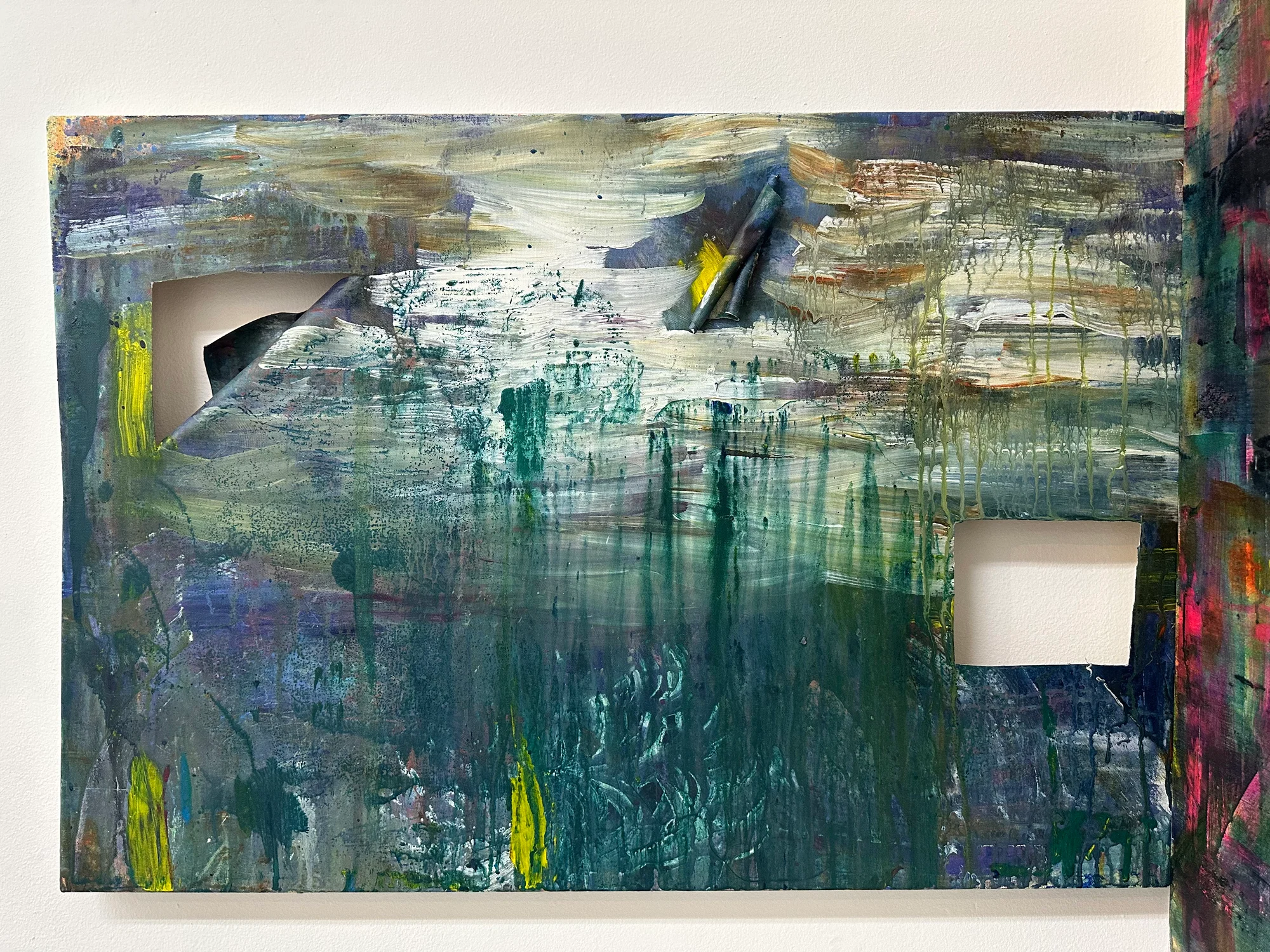 An abstract painting with holes cut out, one of the holes pieces stuck on upper center of painting.
