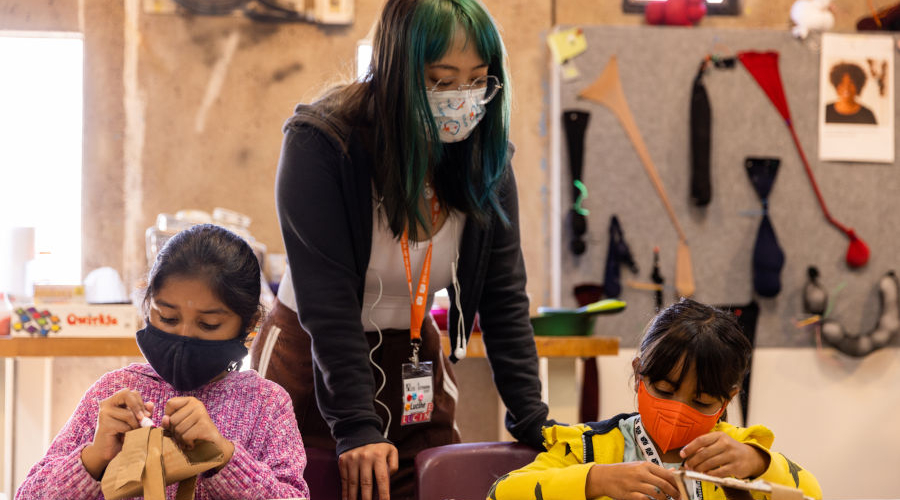 A teacher watching two school chdren working on an art project