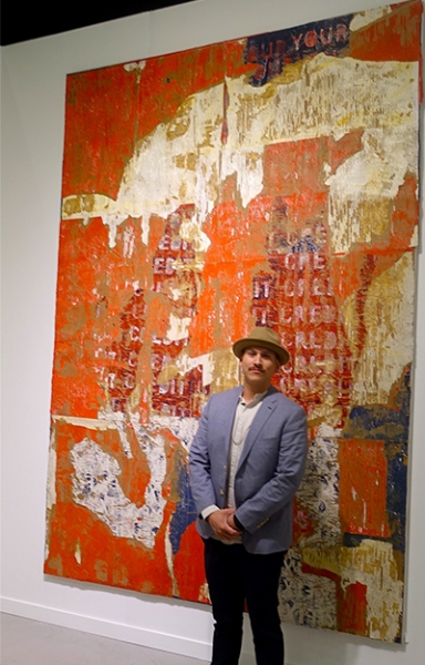 Otis College alumni Edgar Ramirez at Frieze L.A. beside one of his paintings
