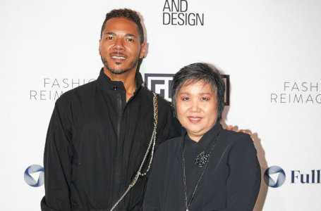 A man and a woman pose in front of a photo-op backdrop at the Los Angeles Fashion Week