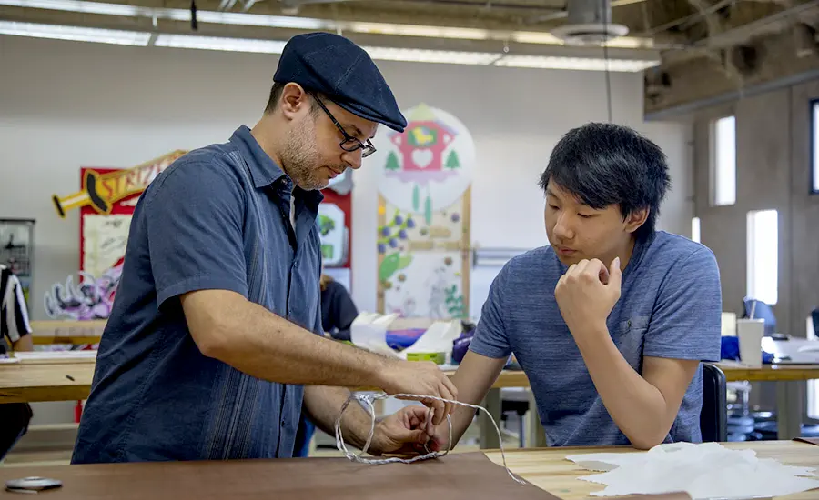 Markus Maciel, left, helps a student with a toy design project.