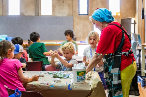 A Summer Youth Camp instructor leads a group of students working on their clay projects.