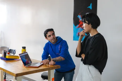 Two students discussing a design project showing on a computer.