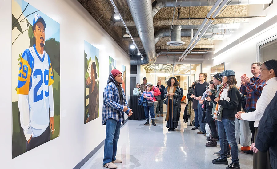 Alum Noah Humes discusses his work at a reception on campus.