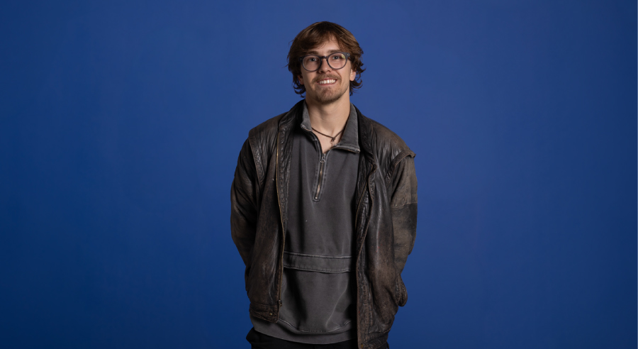Otis College student evan Fecko stands against a blue backdrop.