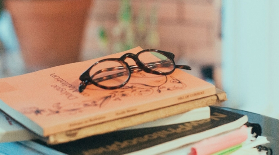 photos of books stacked up with reading glasses on top