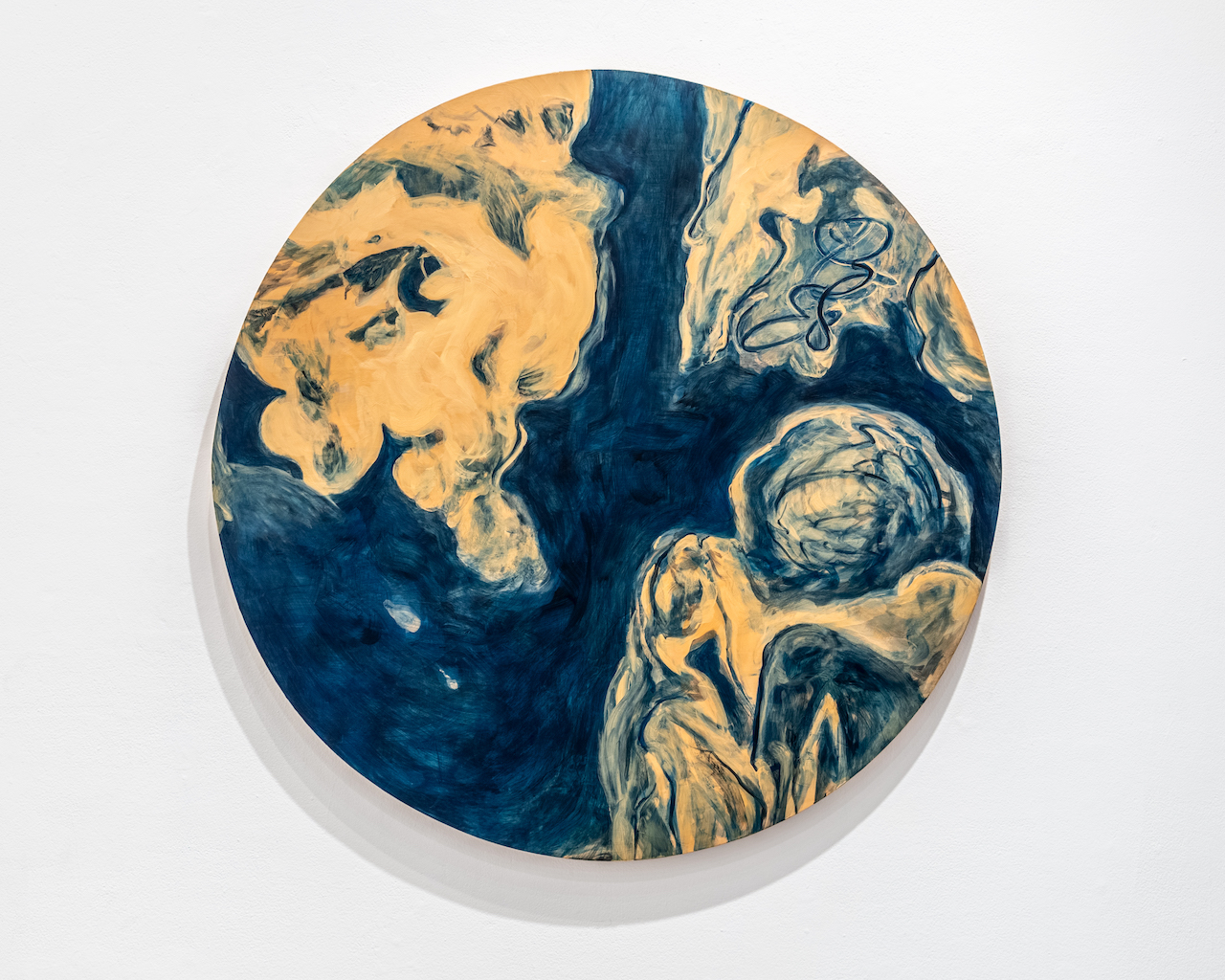 An abstract tondo (round painting) in cyanotype blue and sand. Almost looks like a planet, with the "continents" being feminine bodily shapes, golden sand in color with blue swirls.