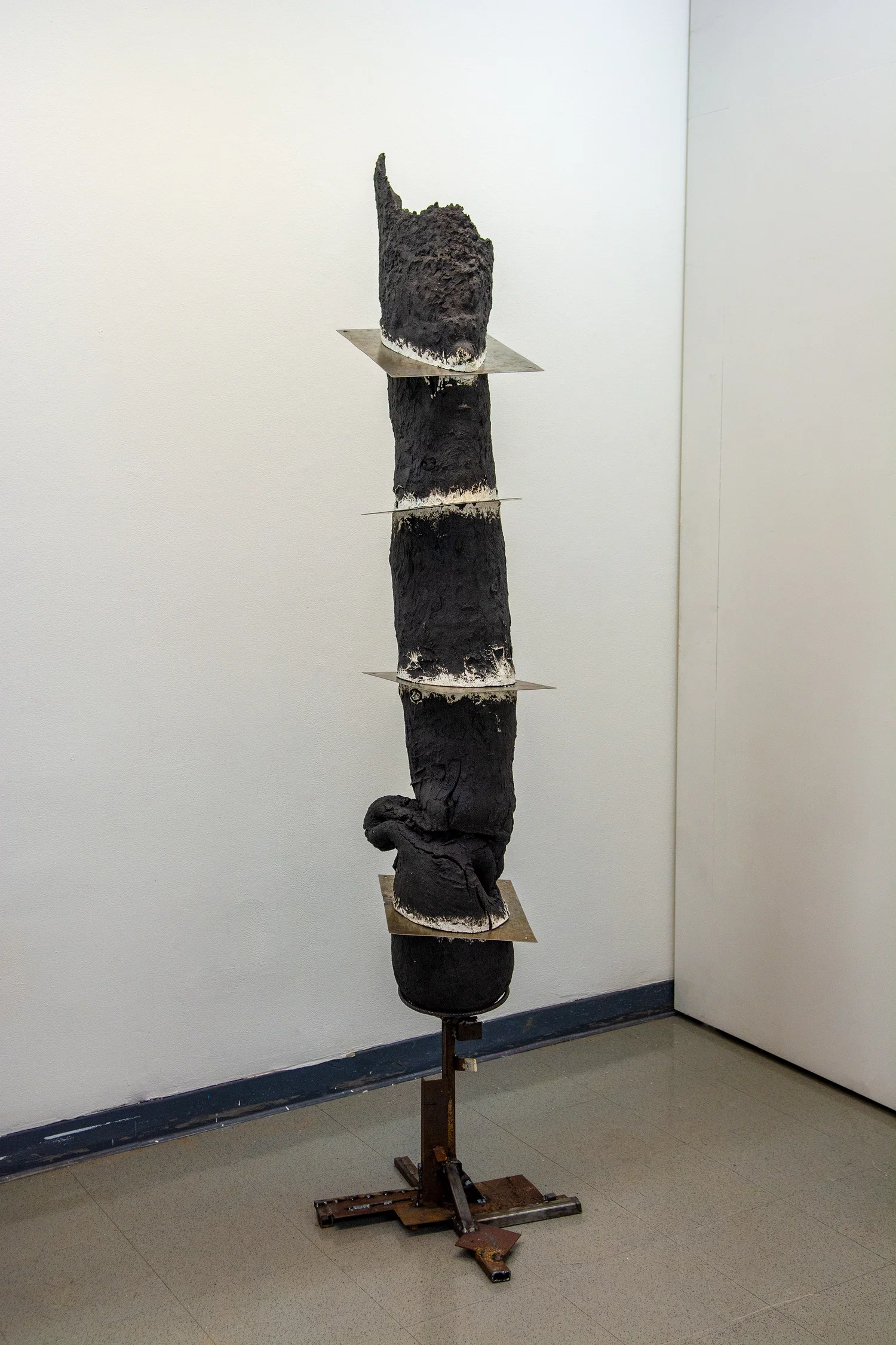 7 foot tall black ceramic pillar. Cut horizontally into 5 pieces by steel plates, none of the plates are level. It's held up by a short rusted steel structure.