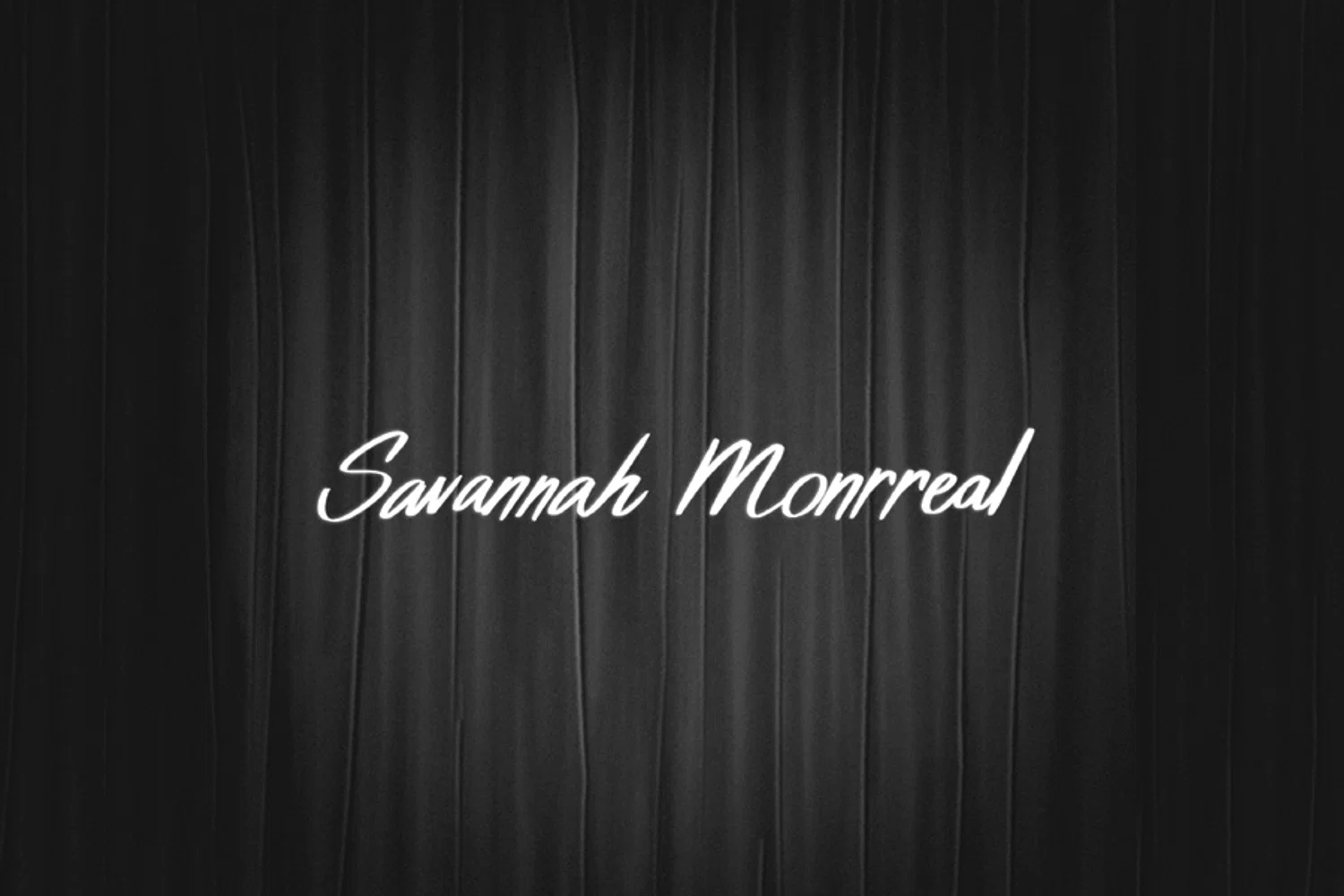 Dark curtain backdrop with white cursive text "Savannah Monrreal" placed in the center