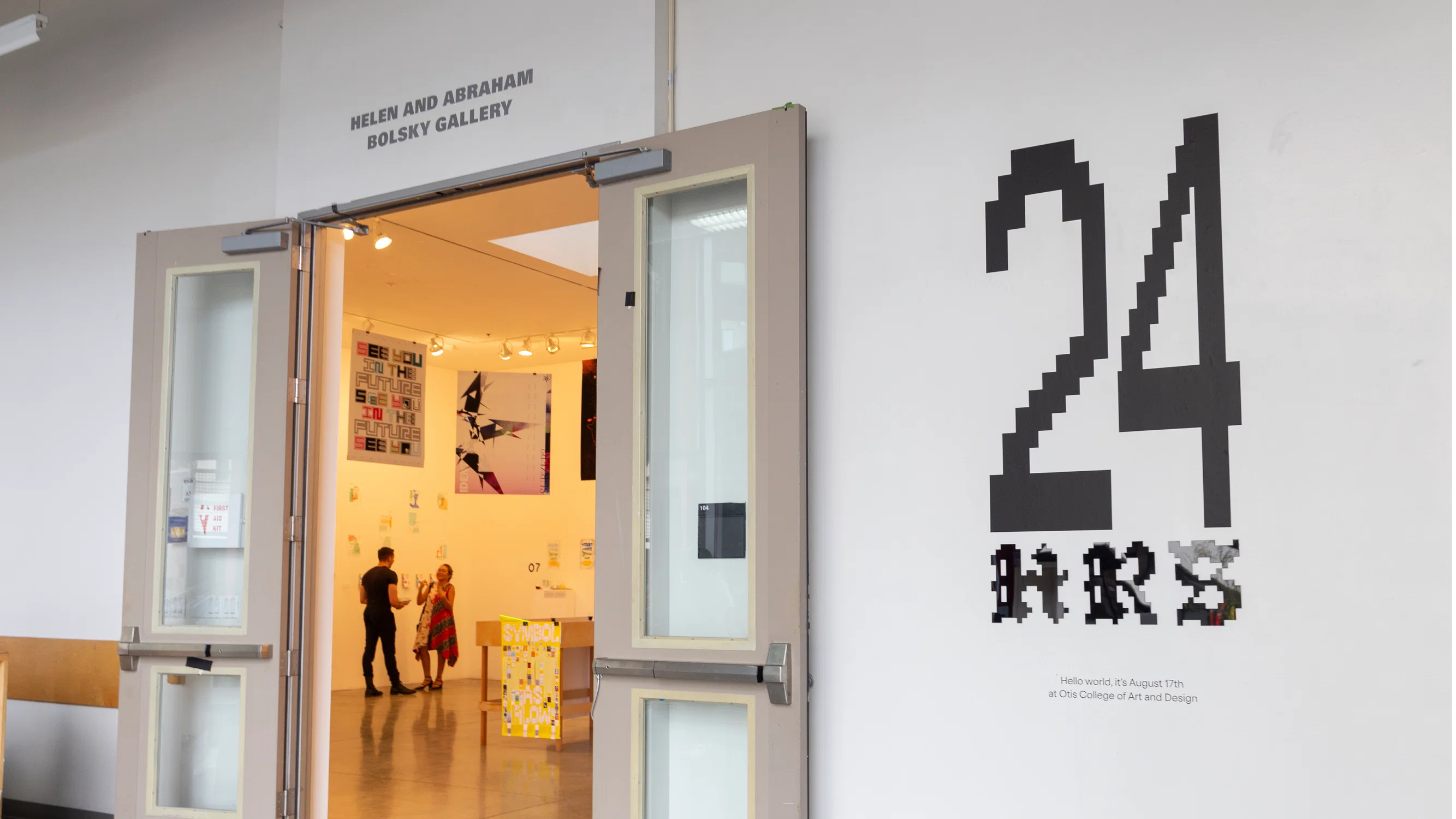 This is an image of the Bolsky Gallery, highlighting a large wall Graphic that reads '24 hrs: hello world, it's August 17th at Otis College of Art and Design"