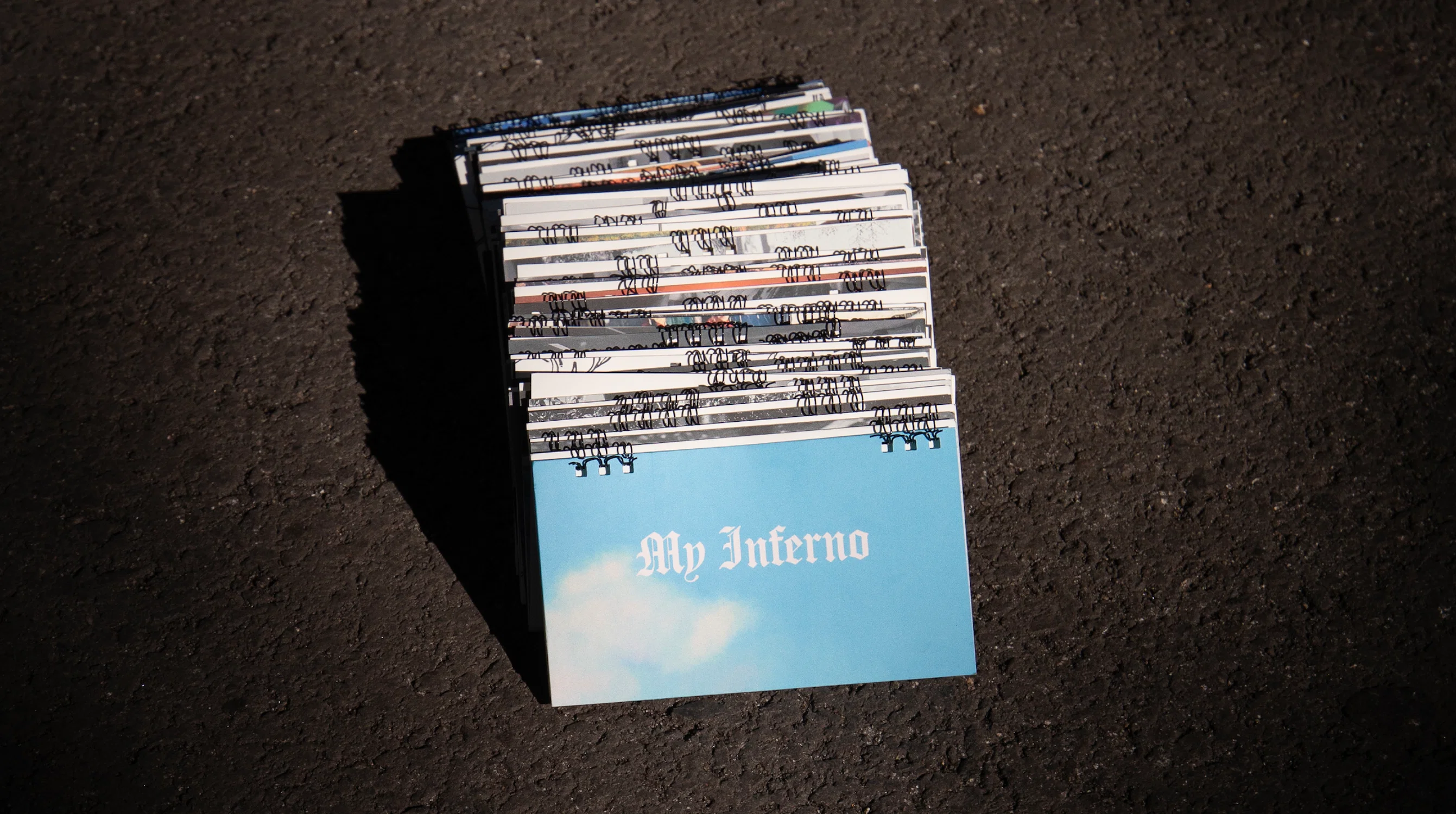 Cover of a spiral bound book titled "My Inferno." It has a blue sky with clouds on the front