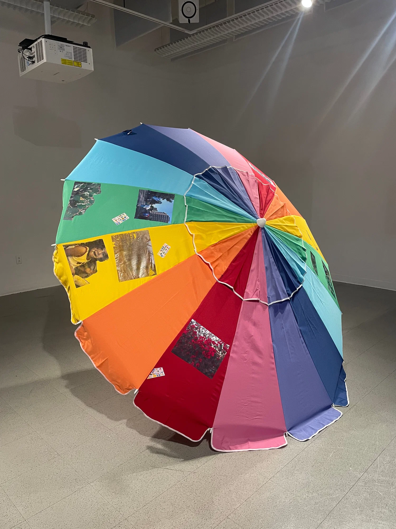In this image includes an image of a rainbow umbrella covered in various image pulled from the artist family archives.