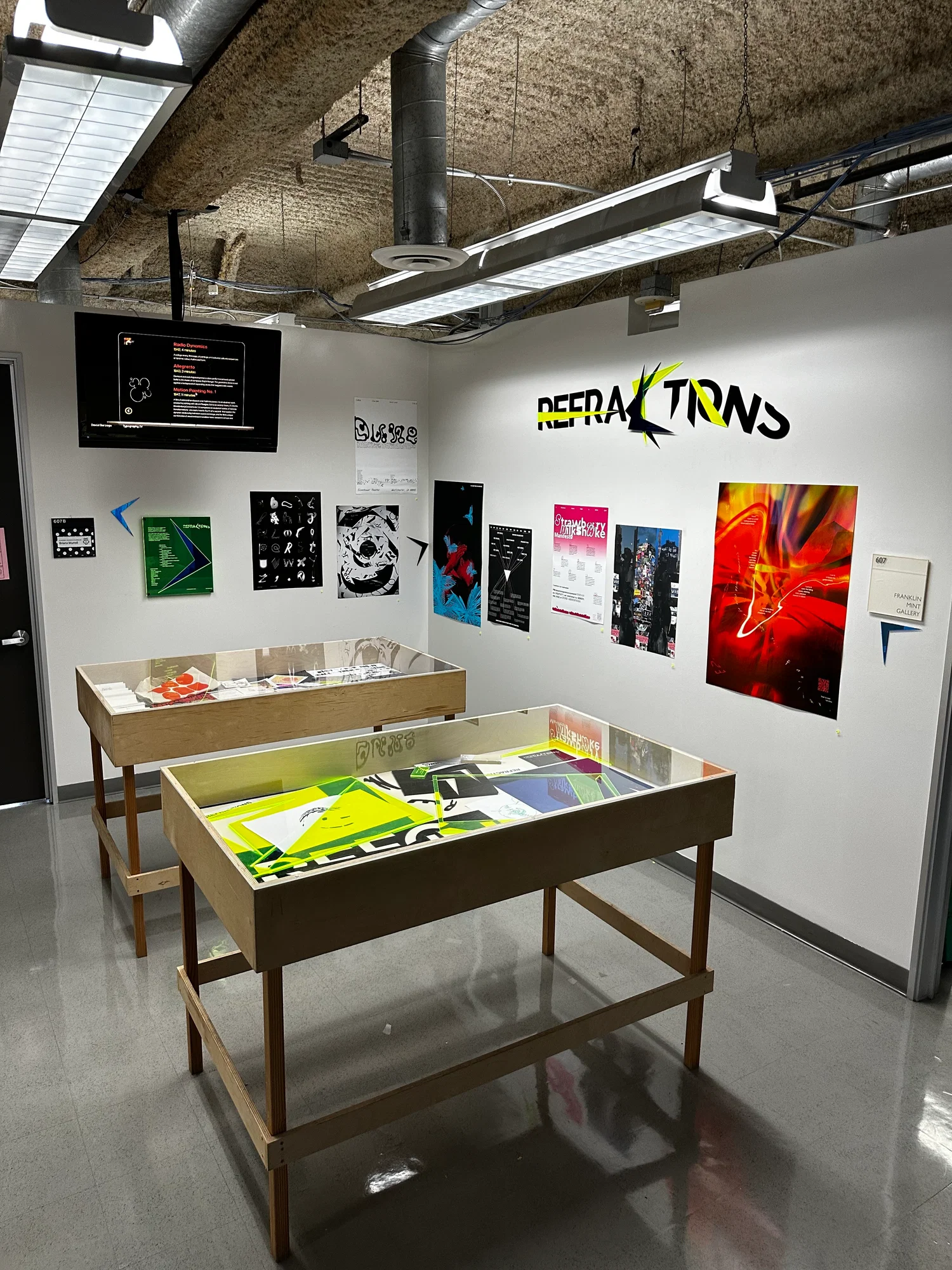 An exhibition of various pieces displayed on the walls as well as two vitrines displaying additional work