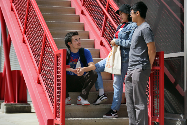 Three students talking together on the stairs outside