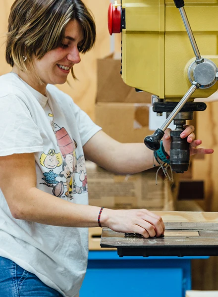 Student working on wood, using machines.