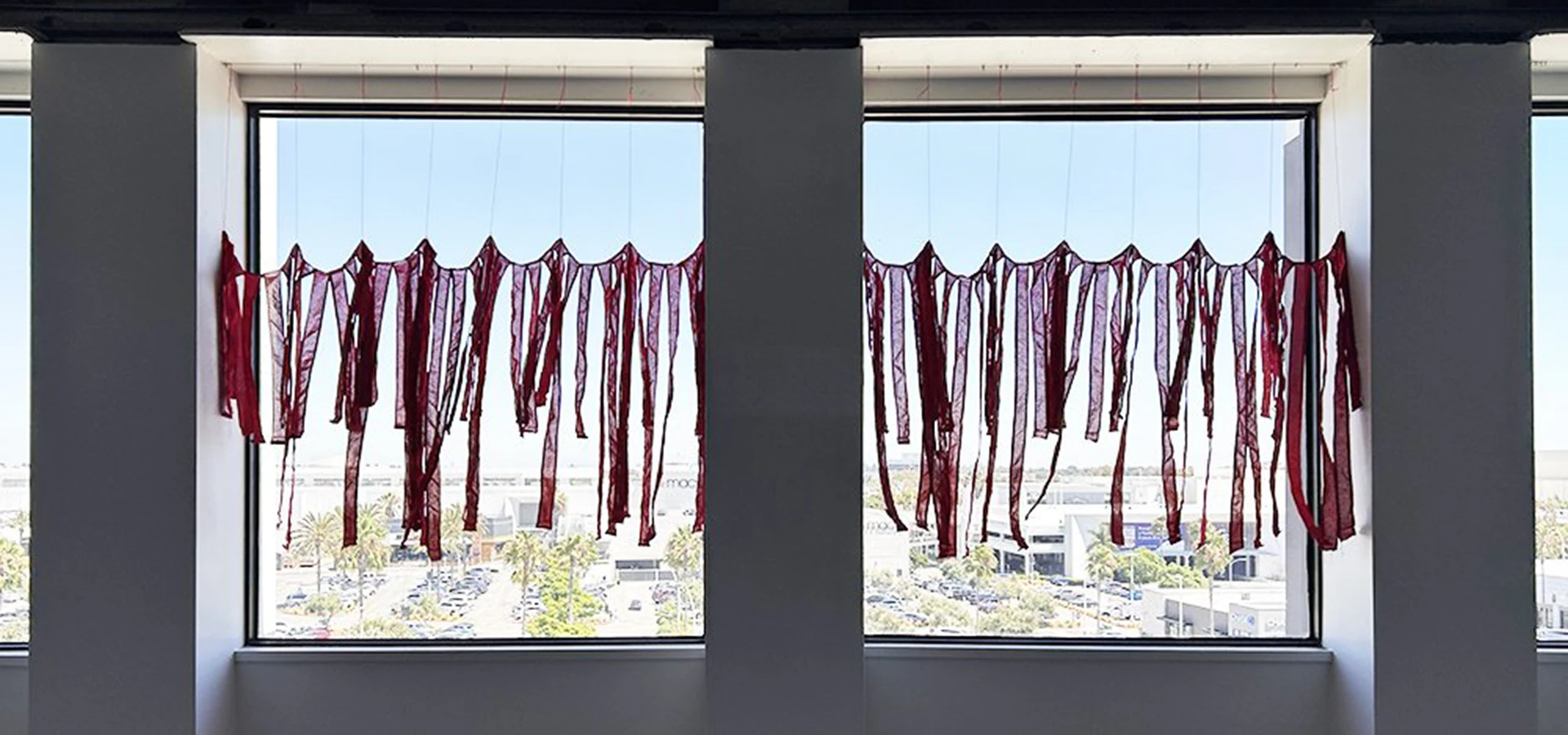 How Can You Celebrate at A Time Like This?. 2024, site specific installation w/ red stripes from deconstructed American flags, approx. 60" x 37" each. Installation view at Nomad III, Torrance Art Museum at Del Amo Crossing, Torrance, CA.