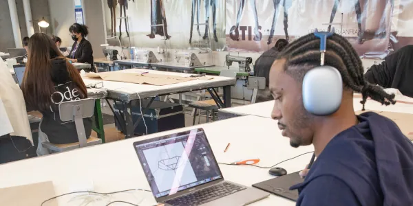 Male student working on a fashion illustration on his computer