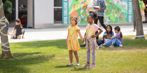 Two female Summer Youth Camp students holding hands in the Otis Commons