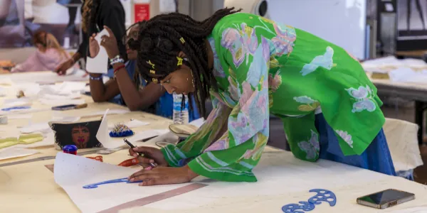 Female Summer of Art student bent over a work table to begin her graphic design project