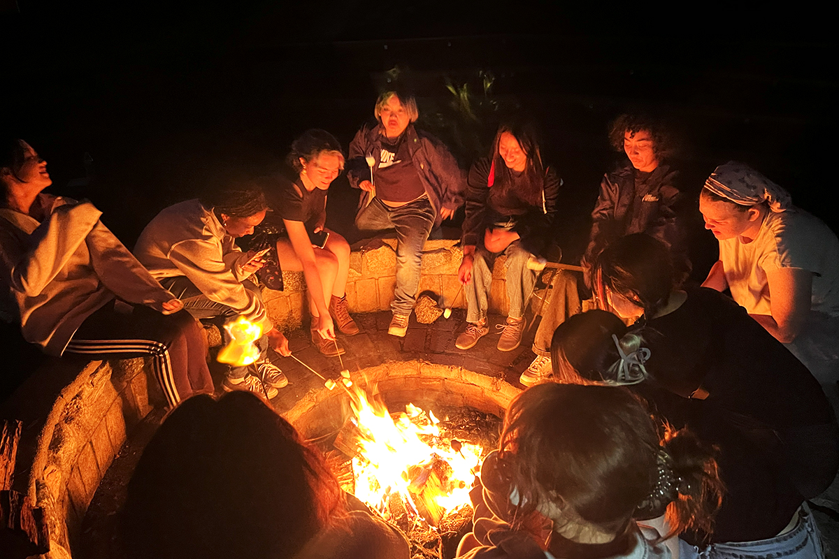 students roasting marshmallows around a fire