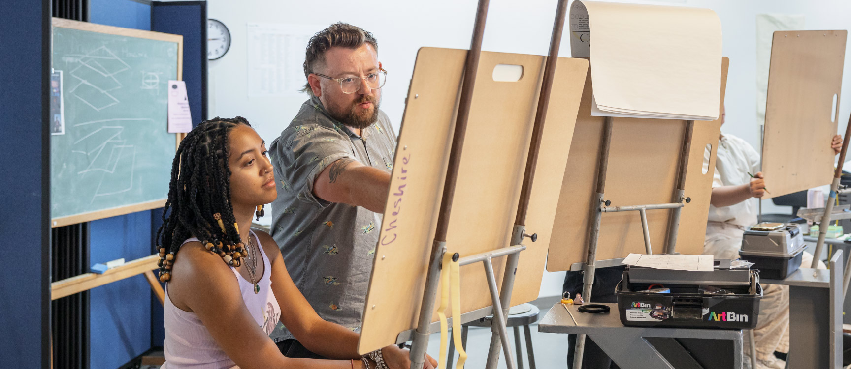 Student and teacher working at an easel