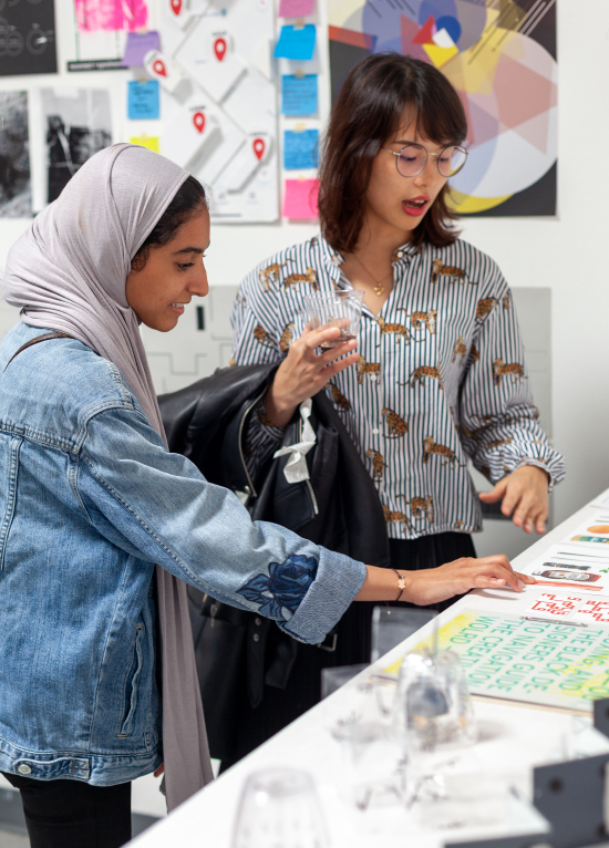 Two students discussing graphic design printed artwork