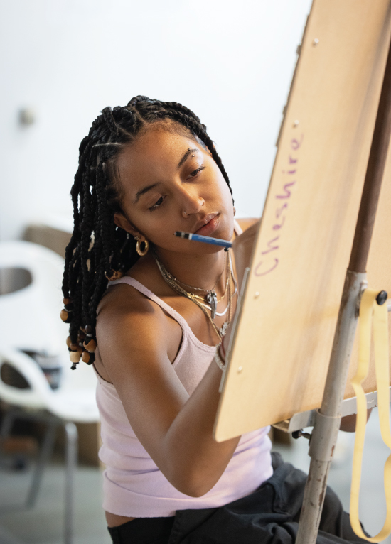 Student drawing at an easel in classroom