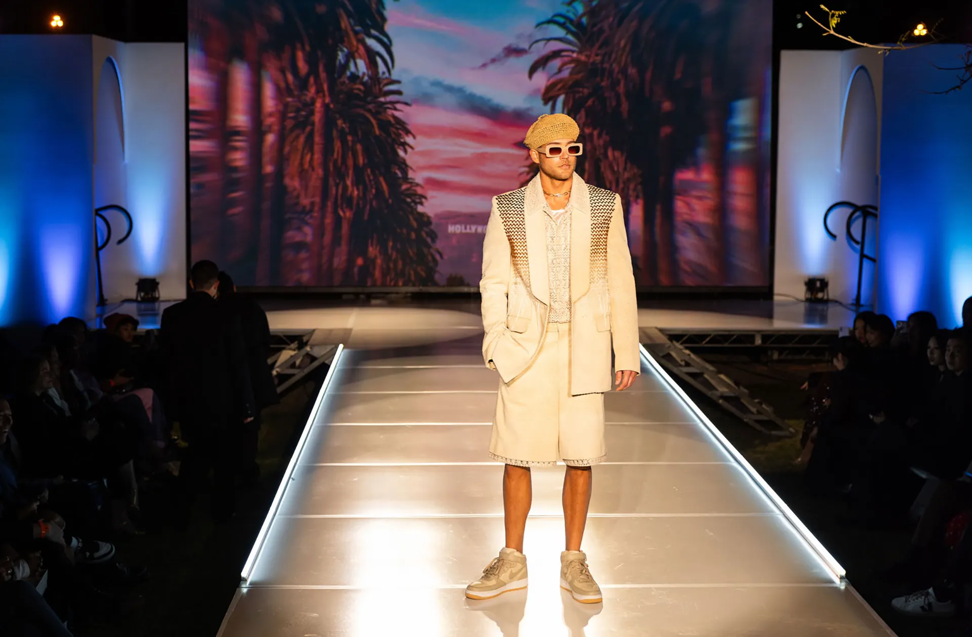 Model on runway in white shorts and jacket